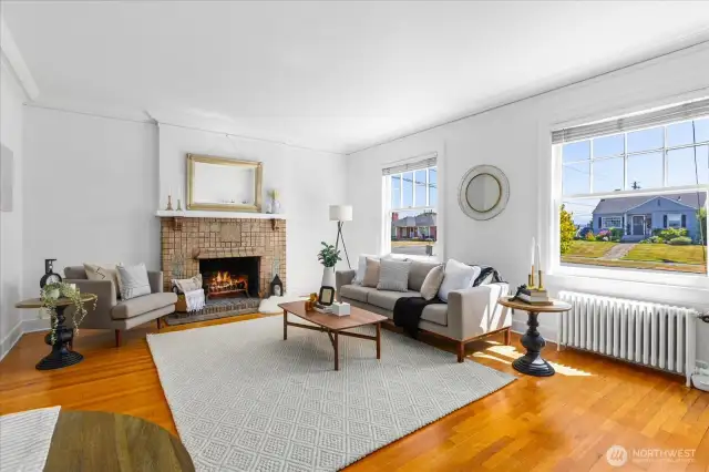 Bright living room area w/original hardwoods, crown moulding & fireplace surround.