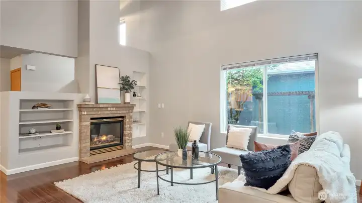 Vaulted Ceiling With Ceiling Fan. The Fireplace Completes The Warmth That The Built-In Book Shelves Add