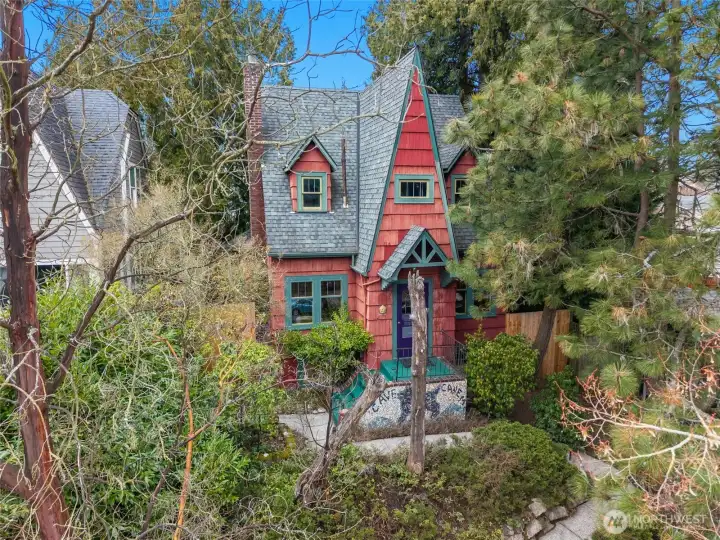 This whimsical Storybook (Fairytale) Tudor is nested among the trees above 35th Avenue SW. Notable architectural elements of this style are the steeply pitched roof, tall chimney and fantasy-like character.