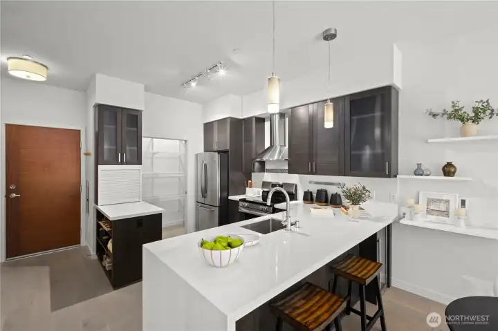 The sleek kitchen is made for gathering, featuring a quartz waterfall countertop and an eat-in peninsula that naturally brings people together.