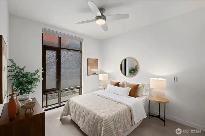 Light-filled bedroom offers an open, airy feel with dramatic windows, customizable privacy via automated dual-direction blinds, a ceiling fan, and a generous walk-in closet.