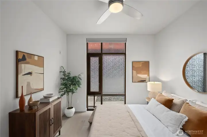 Designed for comfort and convenience, this bright bedroom features floor-to-ceiling windows, automated dual-direction blinds, a ceiling fan, and a roomy walk-in closet.