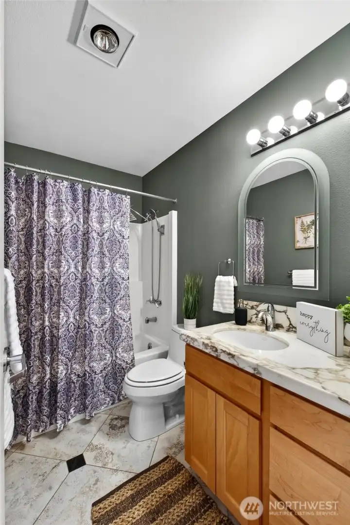 The main level full bath offers tile flooring, a beautiful wood vanity with marble countertop & a newer toilet The main level full bath offers tile flooring, a beautiful wood vanity with marble countertop & a newer toilet