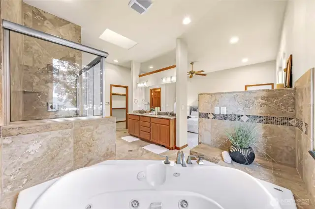 Large jetted tub, and tile up to the ceiling in the shower.