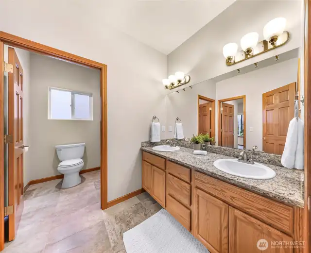 This bathroom connects to a bedroom on the left and another entrance from the hallway. Double sinks and bathtub/shower in the toilet room.