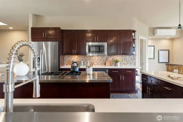 Chefs kitchen with center island, quartz countertops, custom backsplash, stainless appliances.