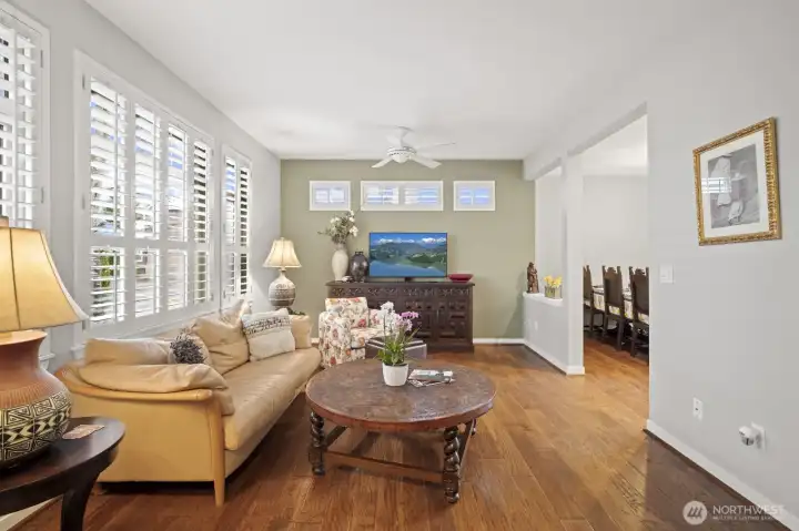 Great room with engineered hardwood floors featuring a gas fireplace, transom and shuttered windows.
