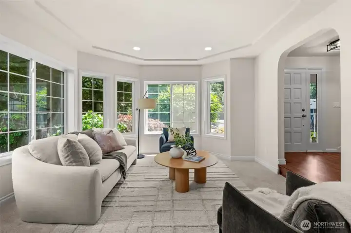 Bay windows frame views of the surrounding greenery and bring the outdoors into this comfortable living area.