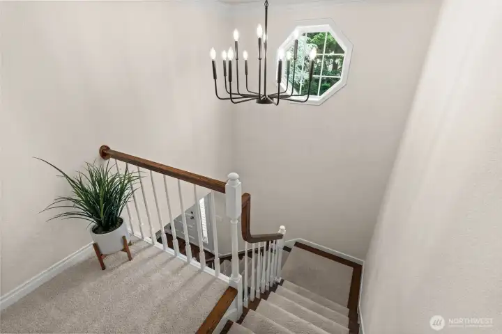 Natural light filters through the decorative window, brightening the stairway and landing area.