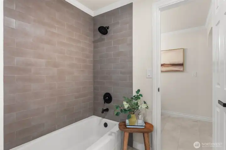 Clean, modern bath includes a tiled shower surround and contemporary black fixtures.