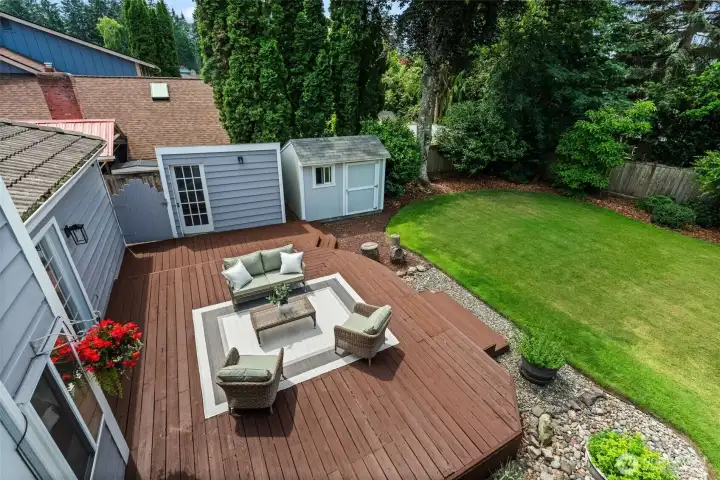View highlights the deck, landscaped yard, and private outdoor setting.