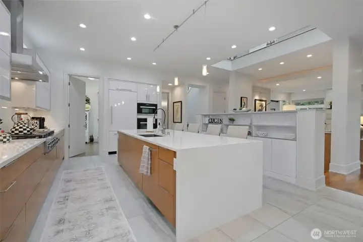 The kitchen is a true showpiece — anchored by a waterfall quartz island and  outfitted with professional Miele appliances.