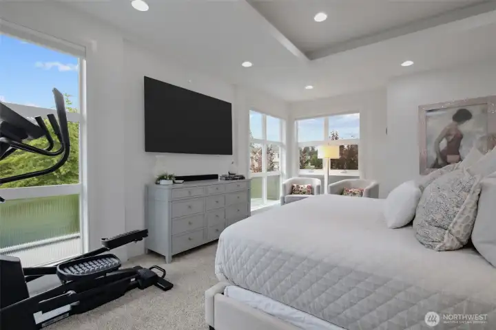Primary bedroom features coffered ceilings, abundant lighting and a deck.