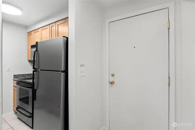 The wall-side of the kitchen has a stainless steel fridge, stainless steel stove/oven, a stainless steel microwave, plus counters and cabinets. Everything is clean and in good condition. Move-in ready!