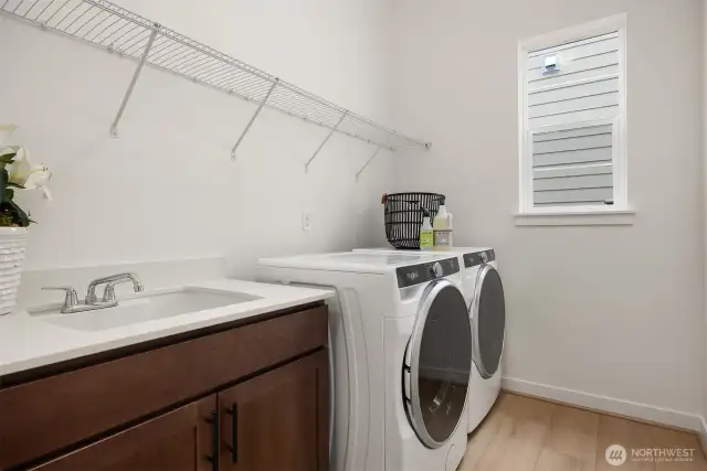Laundry room includes washer, dryer, cabinet with sink