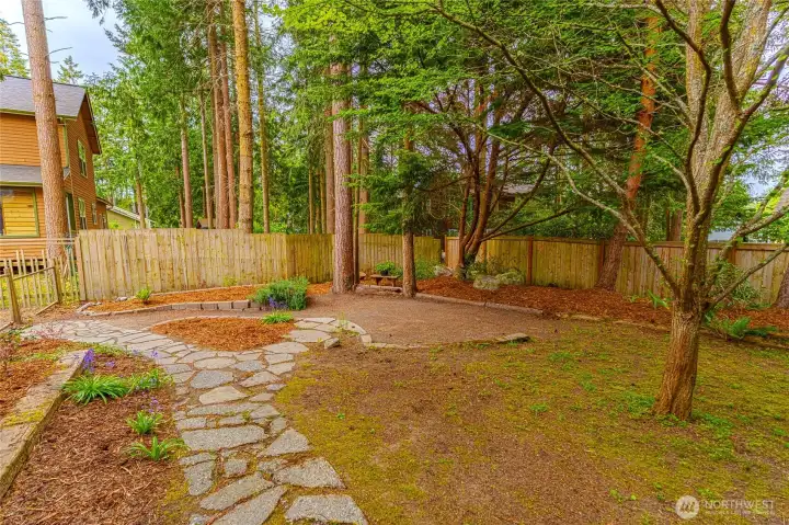 Back yard, newly landscaped with paths.  Paratial fence yard and large trees.