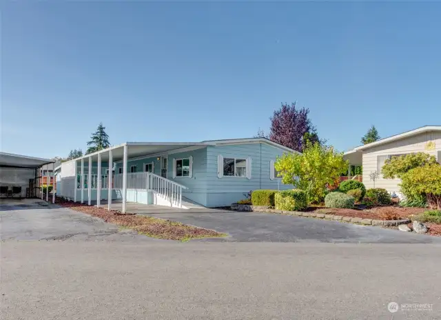 Beautiful landscaped outdoors with ramped entrance leading to front door and large covered patio area.