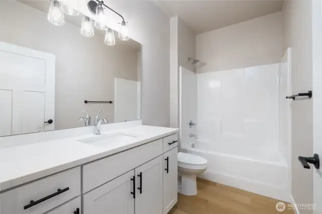 The main bath has taller cabinets with quartz counters.