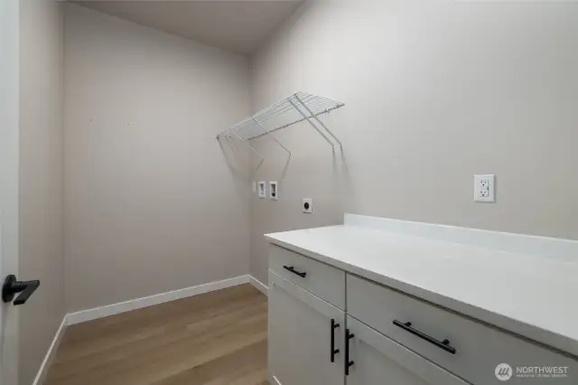 Laundry room has cabinet and folding counter.