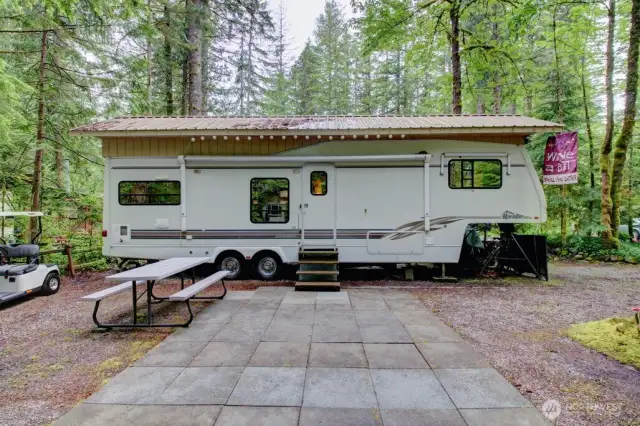 Overhang on trailer and concrete block patio is great to have at this property