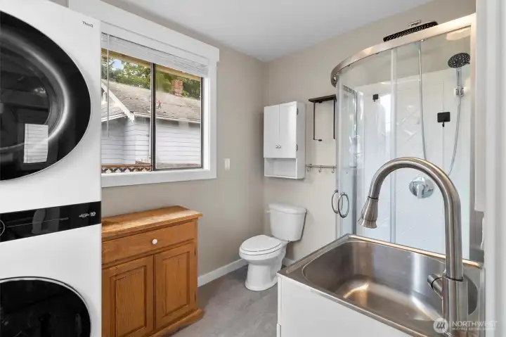 3/4 bath with stacking laundry appliances, large utility sink. This bathroom has blutooth speakers installed.
