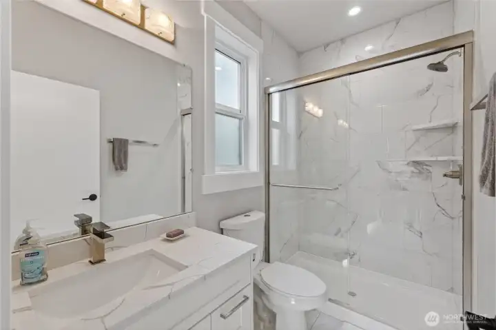 Main floor bedroom's ensuite has glass door, beautiful counters and tiling, and lots of light.