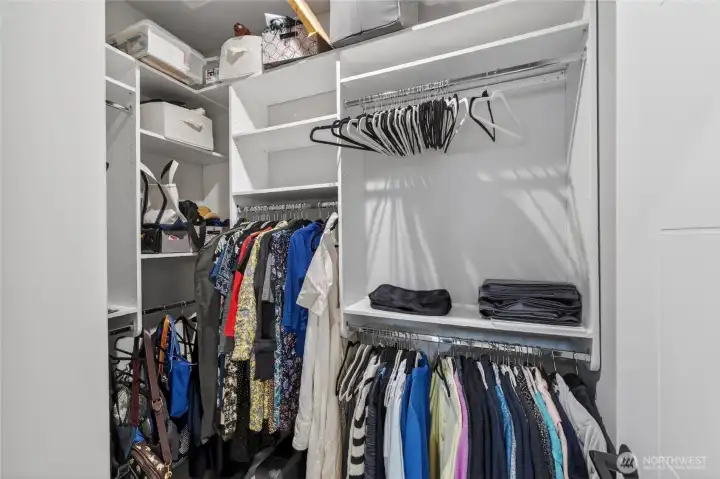 Primary bedroom's walk-in closet has customized shelving and storage.