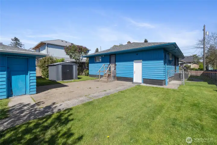 Large flat backyard with additional storage shed and two car garage.