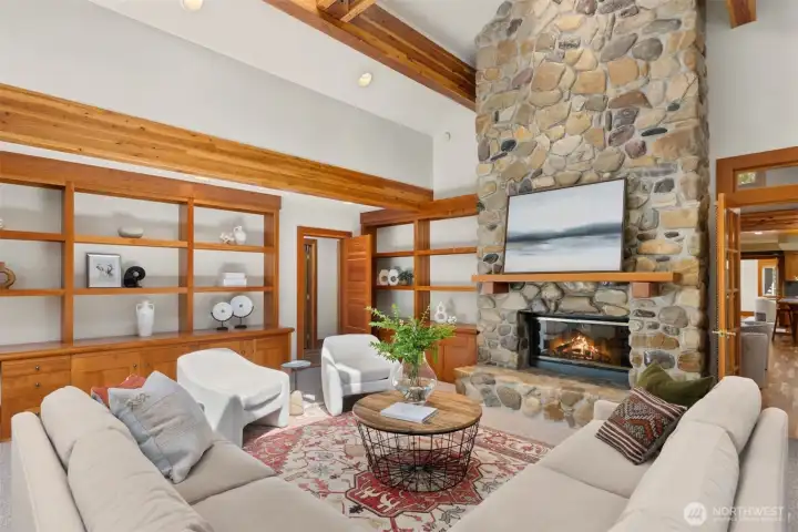 The west living room with built-ins, a river rock fireplace, two story vault ceiling, skylights and transoms.