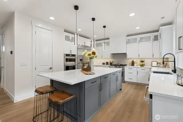 Chef's kitchen with quartz counters, soft close Huntwood cabinets, walk in pantry, beverage fridge, and full height backsplash.