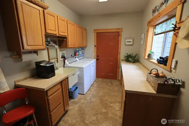 Huge laundry room with full length folding table and tons of storage.  Door leads out to the garage