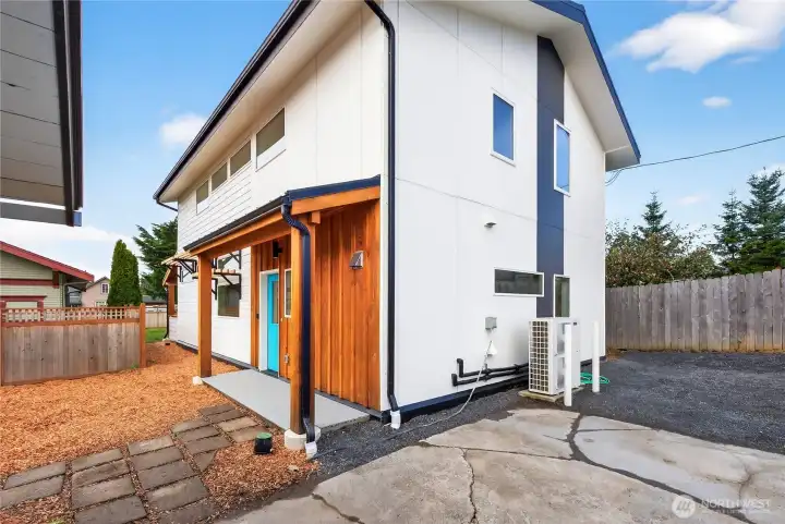 The back of the house featuring flat parking spaces and the side patio.