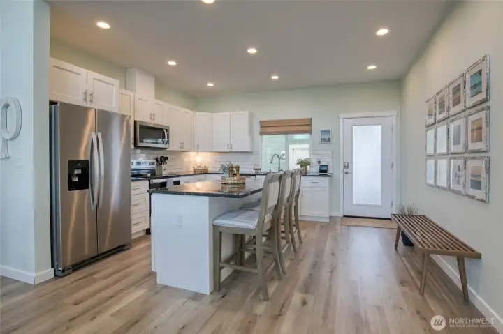 Spacious kitchen with breakfast bar, black granite counters, white subway tile backsplash and stainless steel appliances.