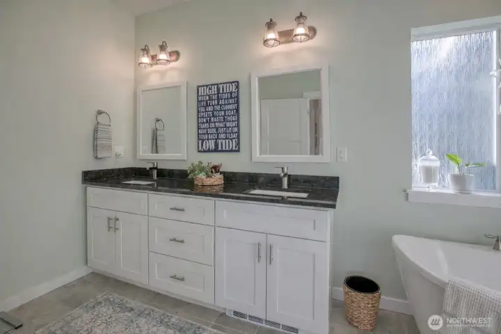 Double sink vanity with black granite counters, automatic under cabinet lighting, and toe kick heater