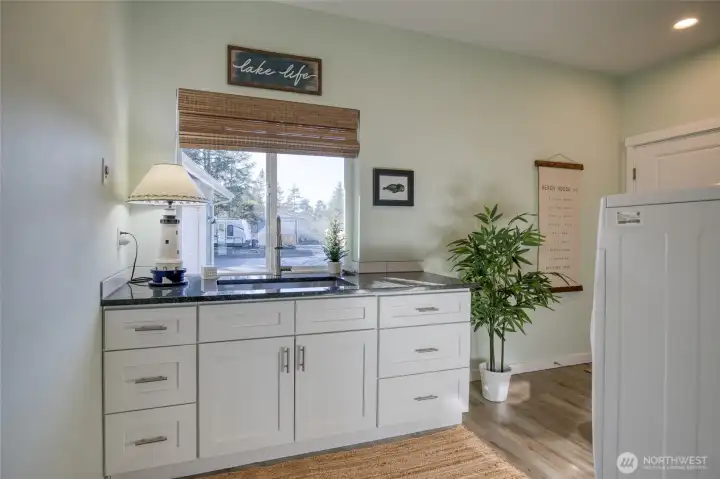 Large mudroom/laundry room with sink/dog washing station and side door access to the backyard