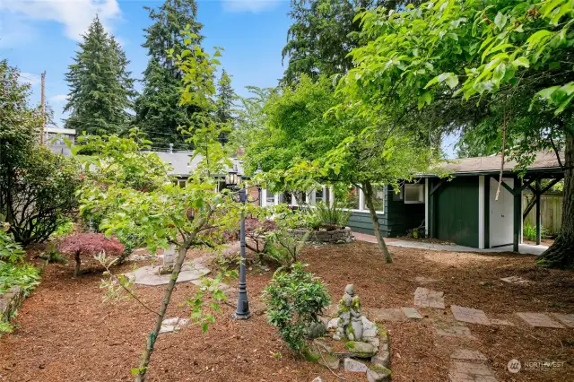 This photo was taken from the very back corner of the lot showing the trees and shrubs and stone walkways that make this back yard so welcoming and private.