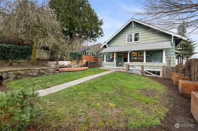 Enchanting backyard is fully fenced, with raised garden beds, a patio, AND the hot tub CAN convey!