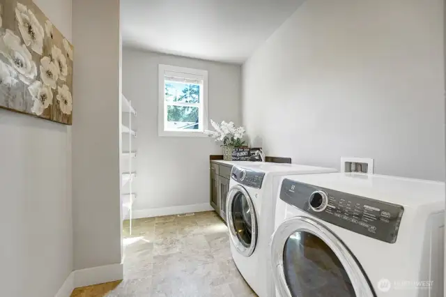The large and bright laundry room is designed for both functionality and convenience. With two newer washer and dryer units, it offers ample storage space, and a sink (with cabinet) adds practicality making it easy to tackle stains or delicate handwashing