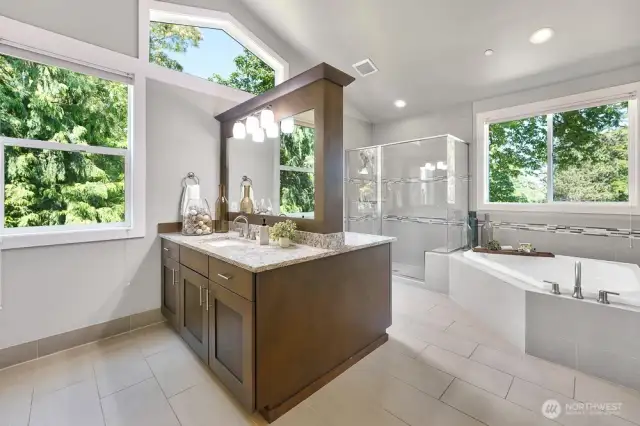 A double vanity in rich Cherry wood brings warmth and sophistication to the bathroom, combining ample storage space with a full-length mirror for both style and functionality. Beautiful tile, abundance of natural light and nothing but lush trees and nature outside