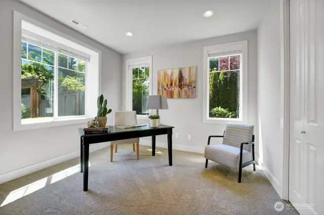 This bright and inviting office offers a perfect balance of natural light and thoughtful design. The large front-facing window welcomes ample daylight, creating an open and airy atmosphere, while the two smaller garden-facing windows provide a serene view of lush greenery