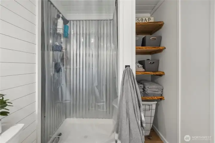 Shower in the bathroom and custom shelving on the right adds to the charm and provides great storage.