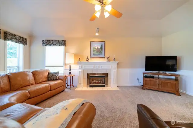 A view of the family room, emphasizing the carpet, fireplace, and ceiling fan/light