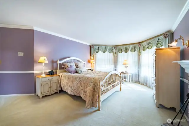 The primary bedroom suite has custom paint, wall-to-wall carpet, chair rail wall detailing and a bay-type window