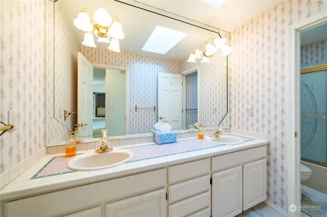 The main upstairs bath features a dual sink vanity with a ceramic tile counter and a wall-to-wall mirror.