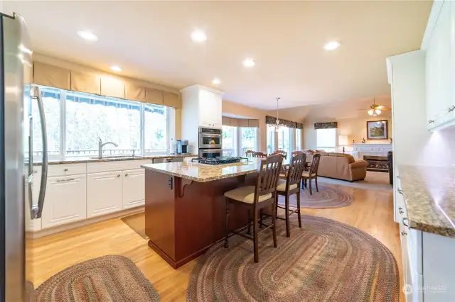 The kitchen features an island with eating bar, a built-in gas downdraft cooktop, granite counters and backsplashes.  There is can lighting overhead and excellent ambient light