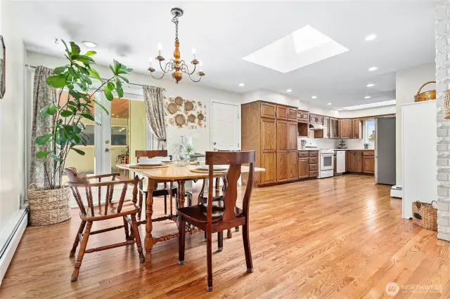 Expansive hardwood and large skylight in bright kitchen/dining area.