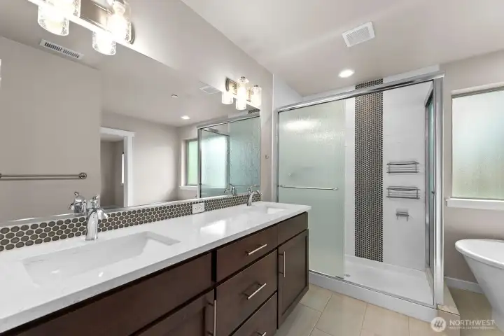 Spa-like en suite bathroom with dual sinks, shower, large soaking tub, & tile floors.
