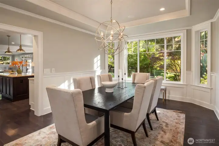 Stylish formal dining room with modern lighting, rich hardwood floors, and seamless flow to the kitchen.