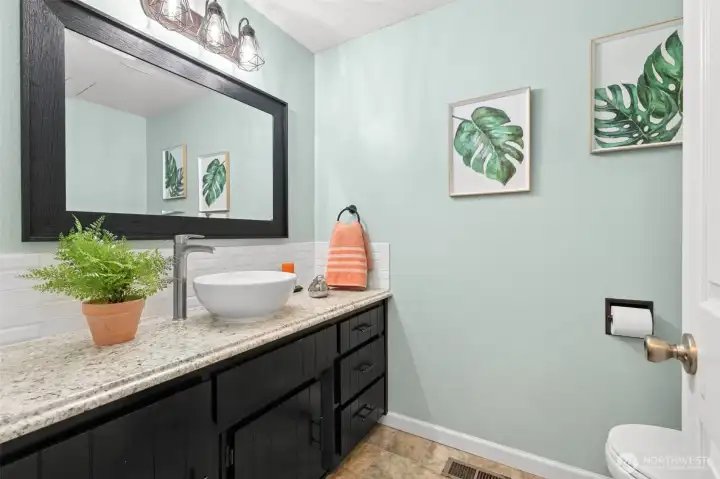A pretty, upgraded half bath expresses the latest looks and color tones  Situated off passage between the entry and the kitchen dinning space, and at the top of the stairs to the lower level living areas.