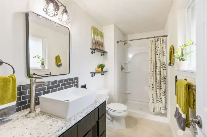 The completely remodeled 3/4 bath off the primary suite offers an extra wide tile shower, easy care flooring, a gorgeous